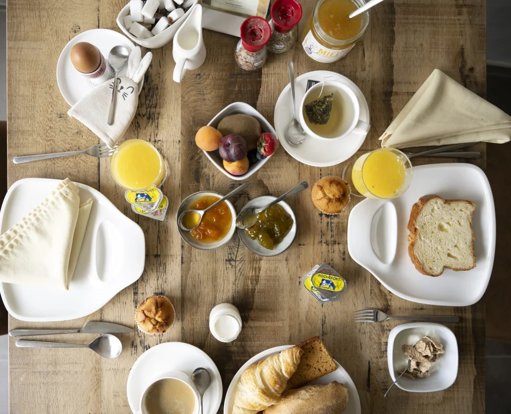 Petit-déjeuner vu du dessus : jus d'orange, viennoiseries, confitures