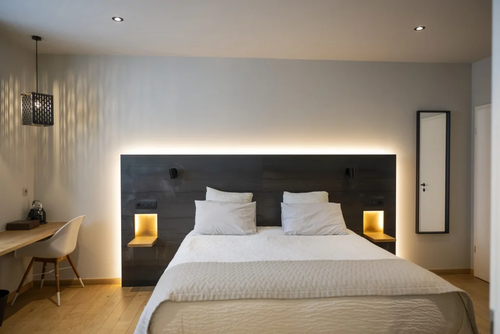 Chambre avec grand lit et tête de lit sombre éclairée