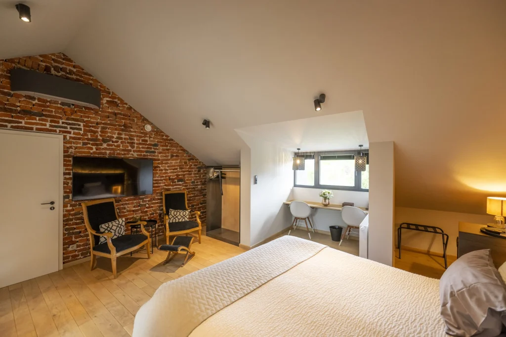 Chambre mansardée avec mur de briques et coin salon
