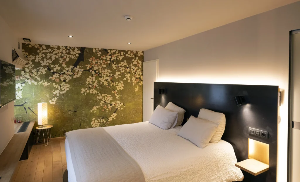 Chambre au papier peint fleuri et tête de lit éclairée